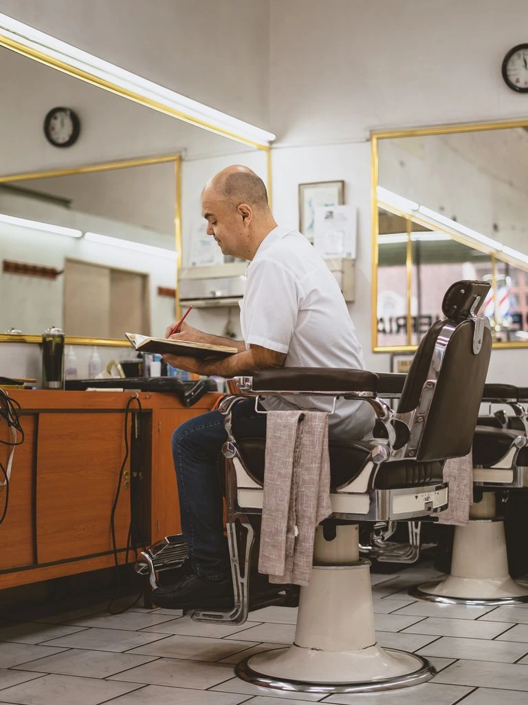A small business owner at a workbench with an open notebook, photographed in warm natural light.